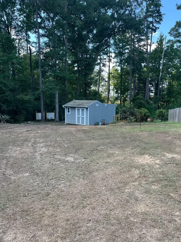 Wooded lot opened up into a usable yard around a small shed after land clearing